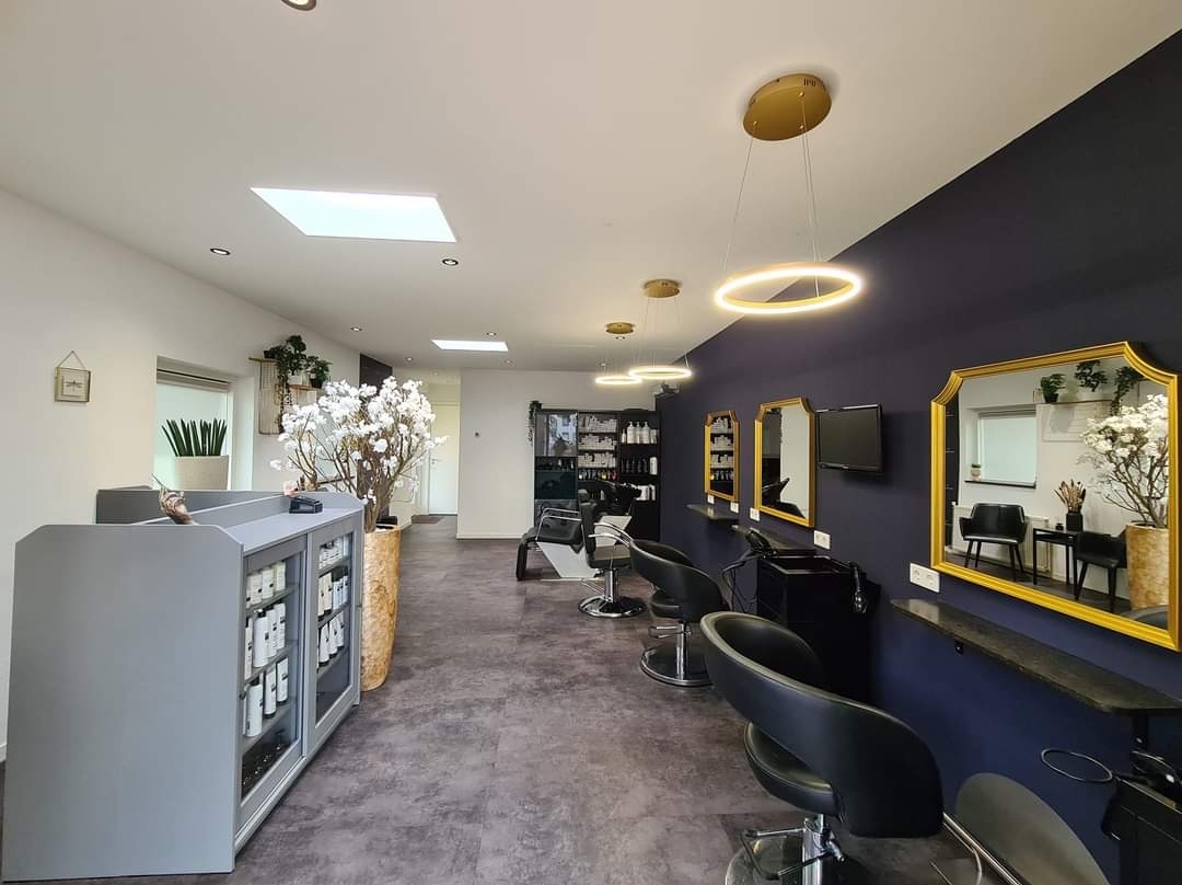 De salon: balie, kappersstoelen, goudkleurige spiegels en een donkerblauwe wand